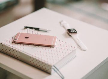 IPhone on a notebook with a smartwatch and pen
