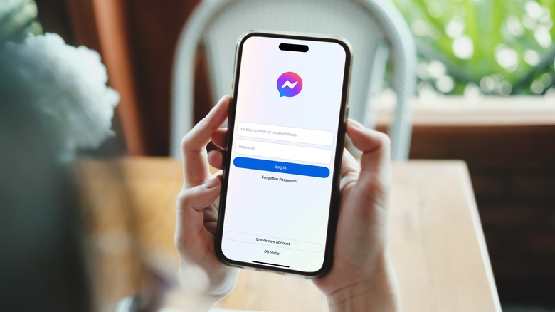 A person's hands holding a phone with the Messenger app open