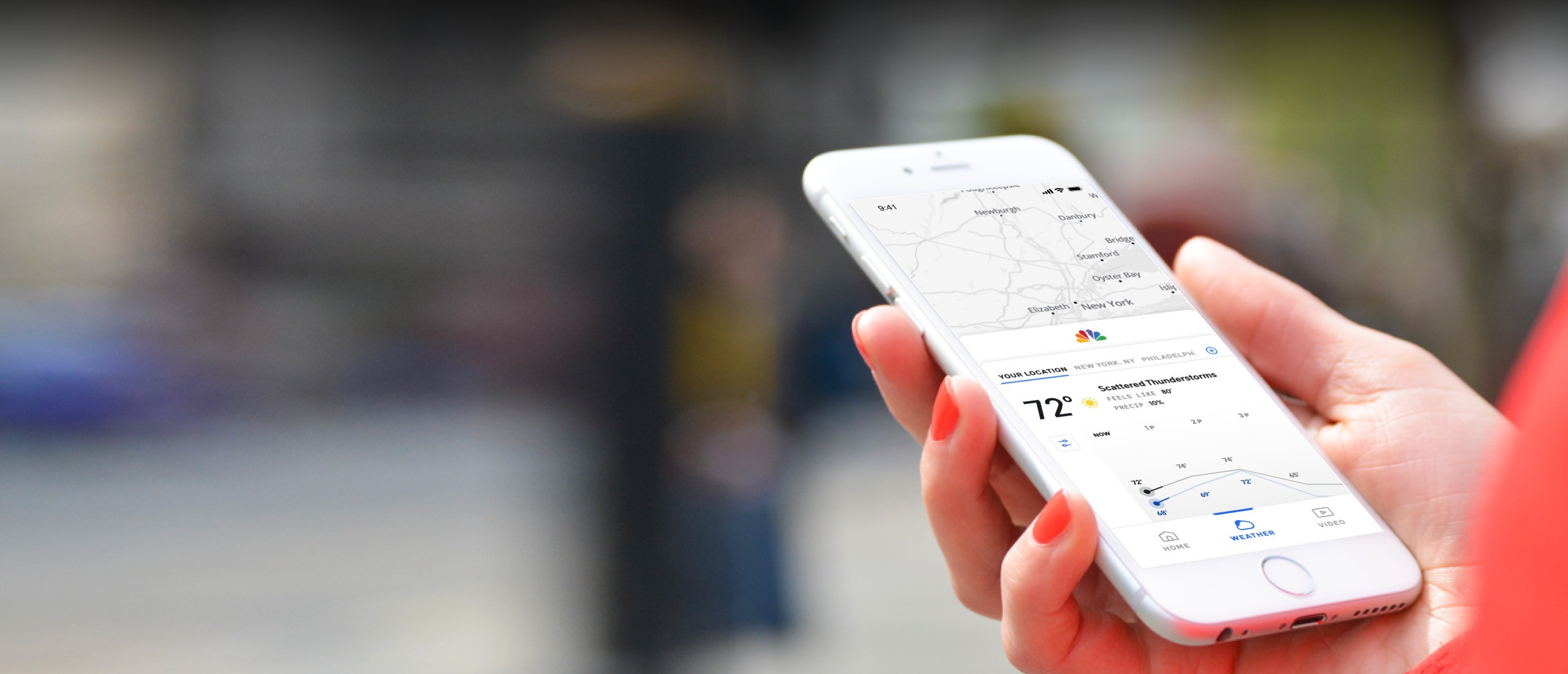 A woman holds a smartphone displaying NBC Connecticut News