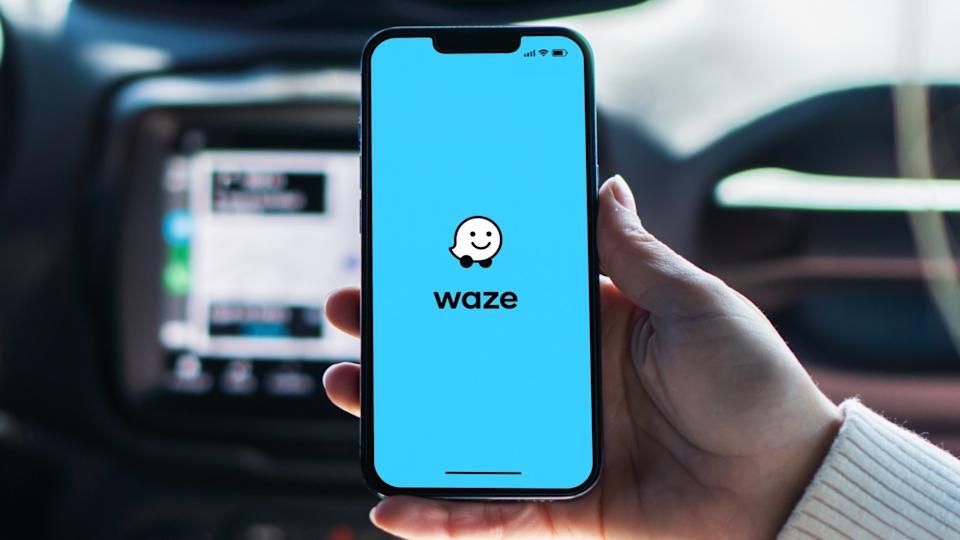 A person holding an iPhone with the Waze app opened