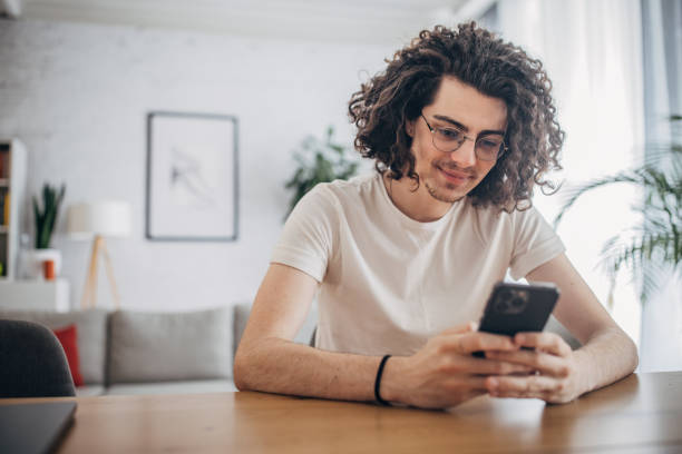A young man sitting at a table and using his smartphone